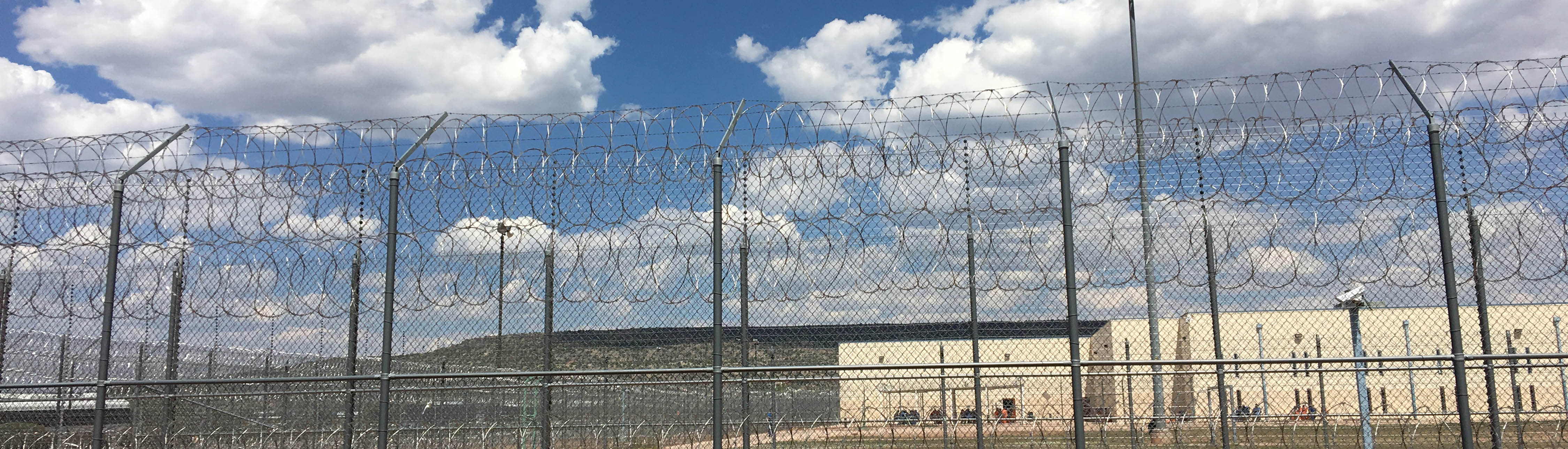 Prison in the distance behind a long barbed wire fence