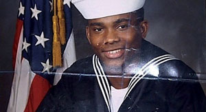 A photo of Howard Bailey in his Navy uniform, with a dark blue background and a U.S. flag behind him.