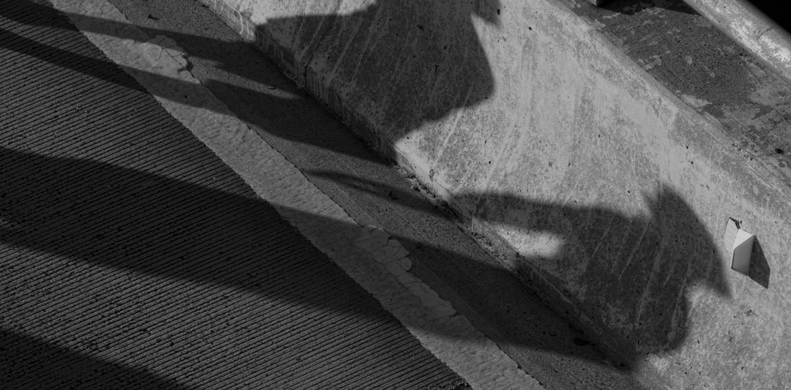 Black and white photo of the shadows of two people on a concrete pavement