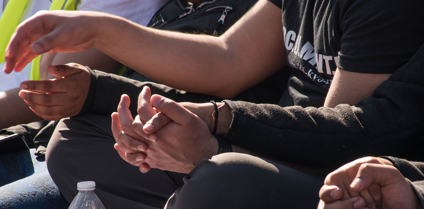 Photo of three people sitting andholding hands, with their clasped hands filling most of the frame.