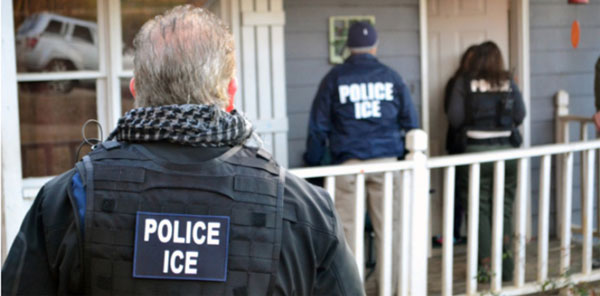 Foto de tres oficiales de ICE acercandose a una casa