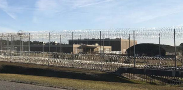 Photo of Winn Correctional Facility - a prison building with a barbed wire fence in the foreground