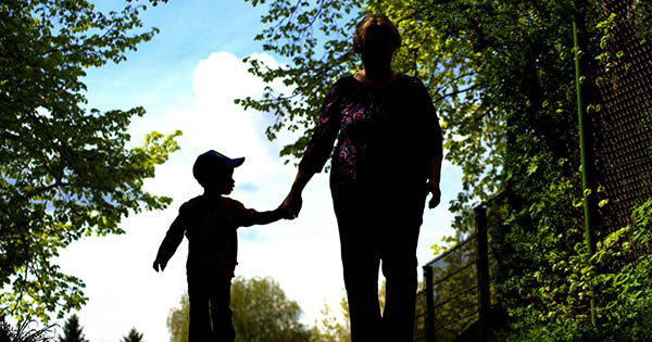 Silhoutte of a mother and child holding hands surrounded by trees