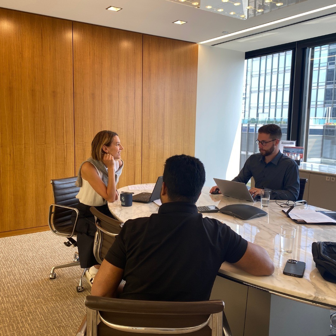 Pro bono attorneys sit at a table across from clients helping them prepare their green card applications.