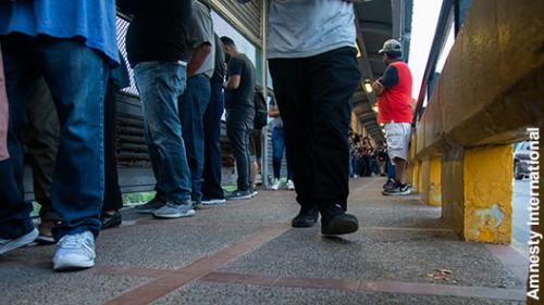 Photo of the legs of people waiting in line near a U.S. port of entry