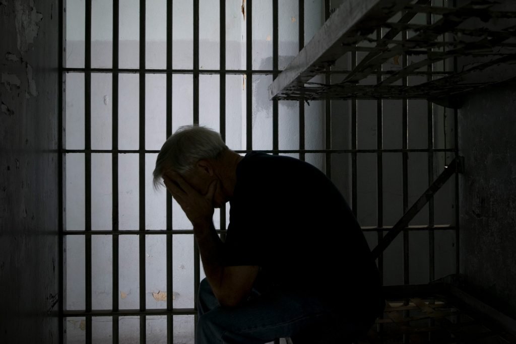 Person in jail with head in hands