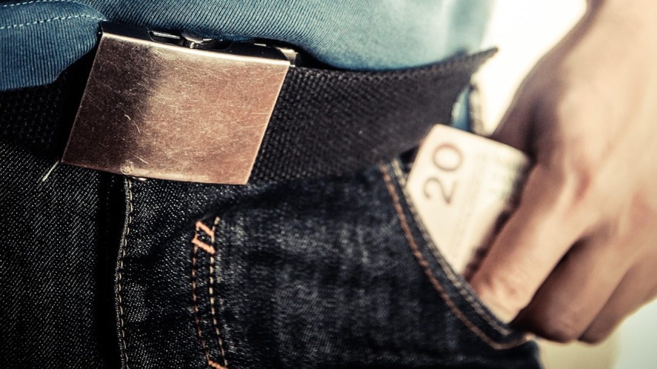 Photo of a person's hand pulling a $20 bill from their pants pocket