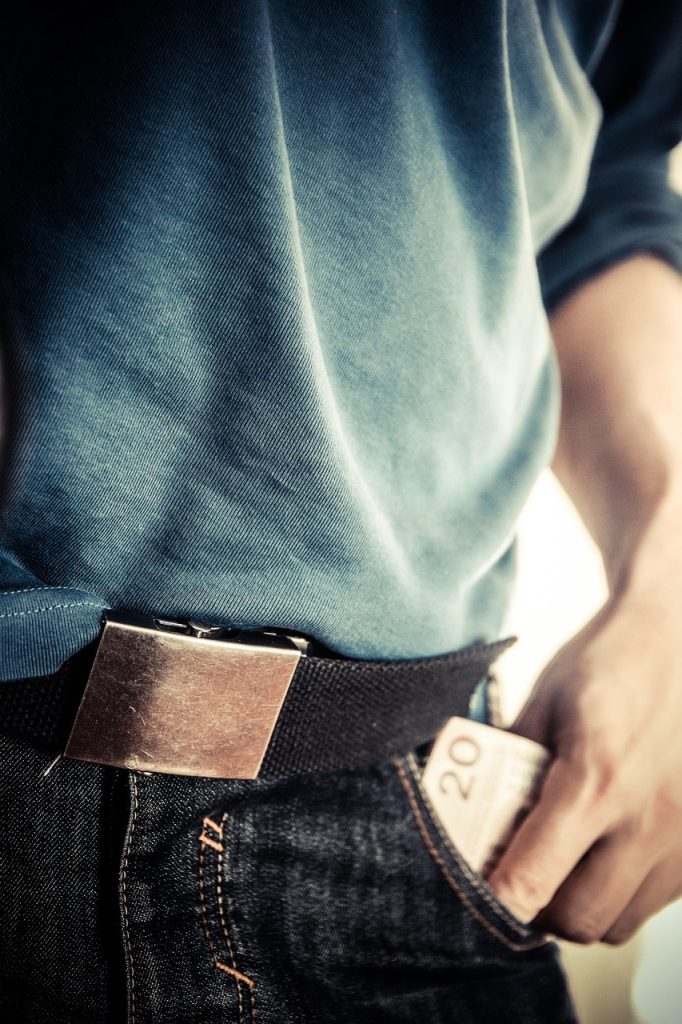 Photo of a person's hand pulling a $20 bill from their pants pocket