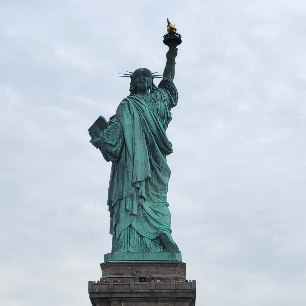 A photo of the Statue of Liberty taken from the back on an overcast day.
