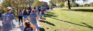 People running outside through a tree lined trail on a sunny fall day in a park at the NIJC 5K in 2025.